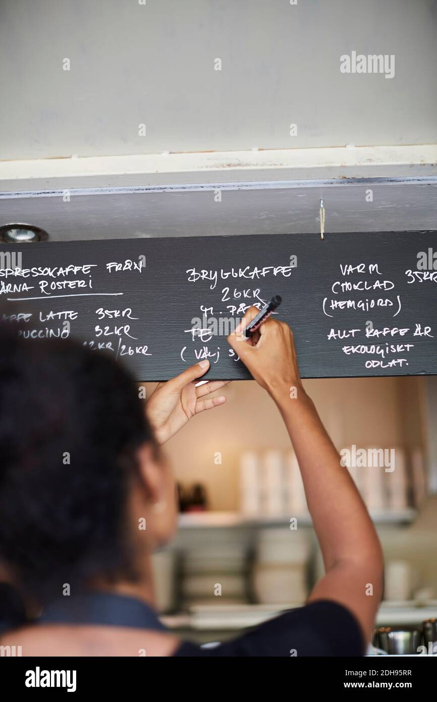 Rear view of waitress writing on menu at cafe Stock Photo