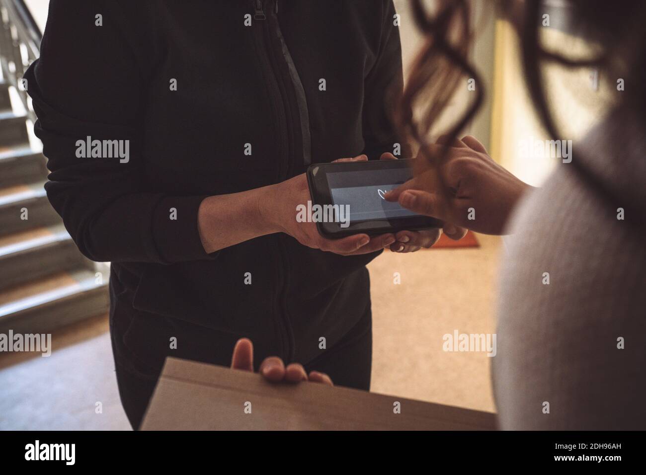 Midsection of customer signing on phone during home delivery Stock Photo