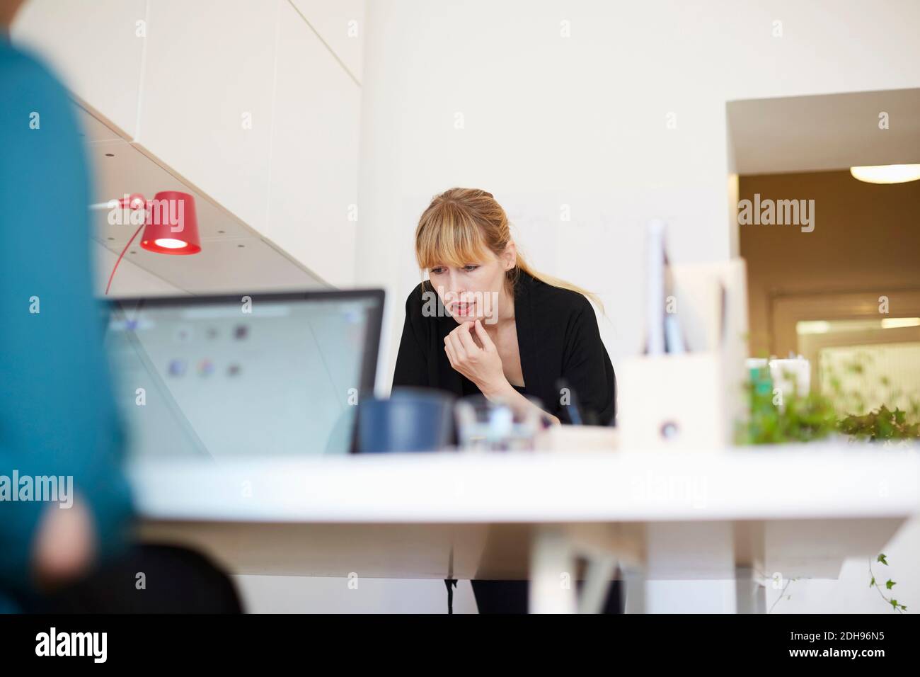 Mid adult businesswoman working at table in office Stock Photo - Alamy