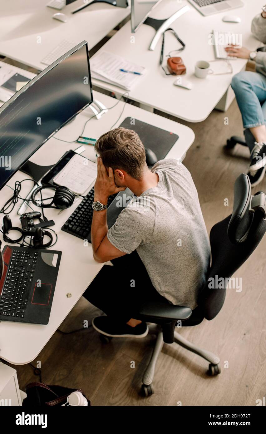 High angle view of computer programmer sitting at table in office Stock Photo