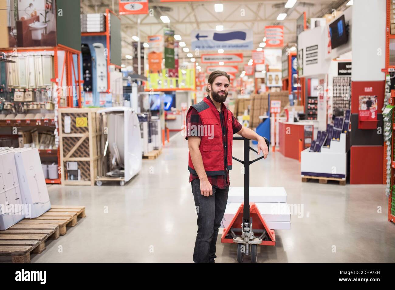 Portrait of salesman standing by handtruck in hardware store Stock Photo