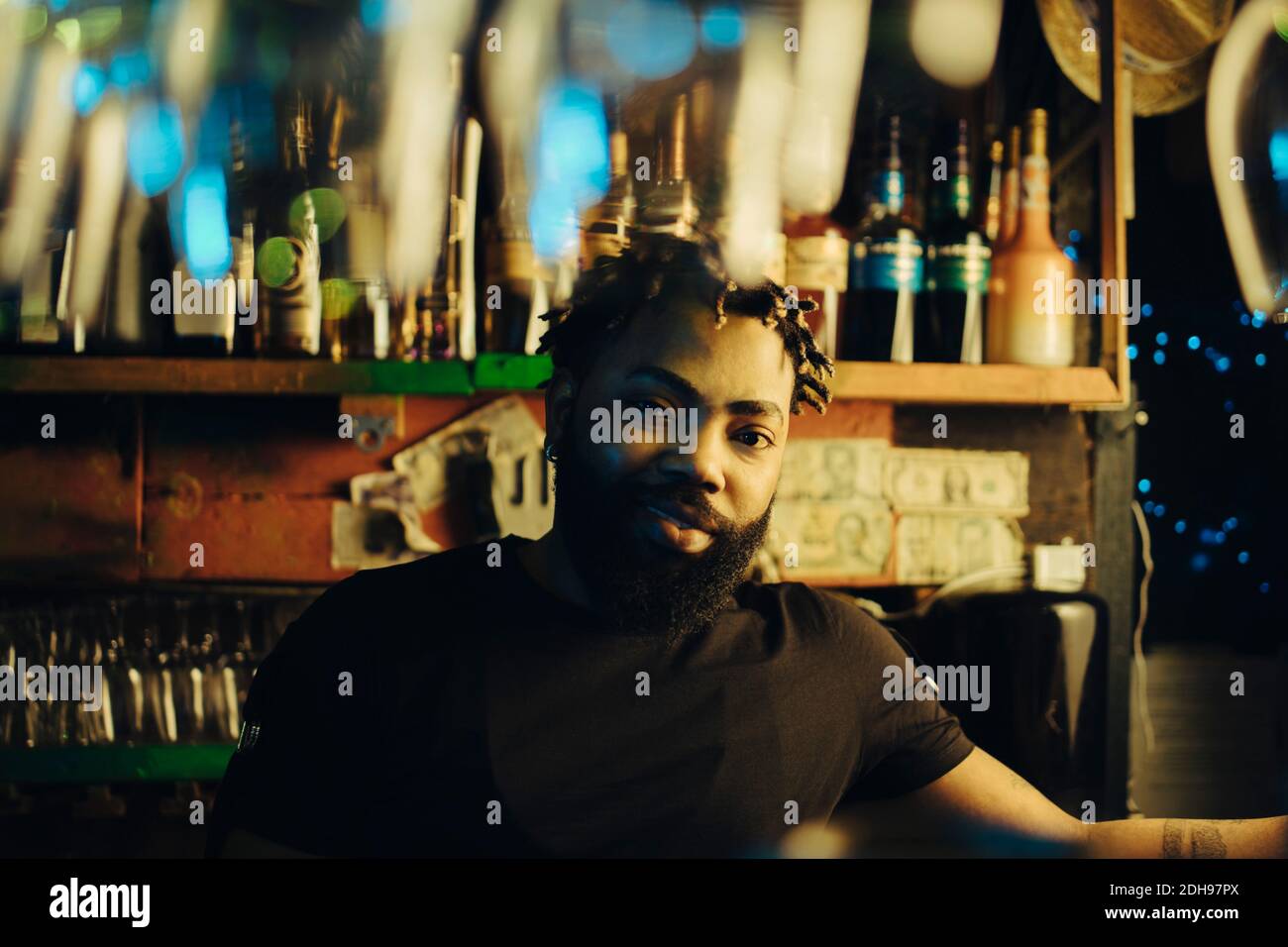 Portrait of confident young afro bartender at illuminated restaurant Stock Photo