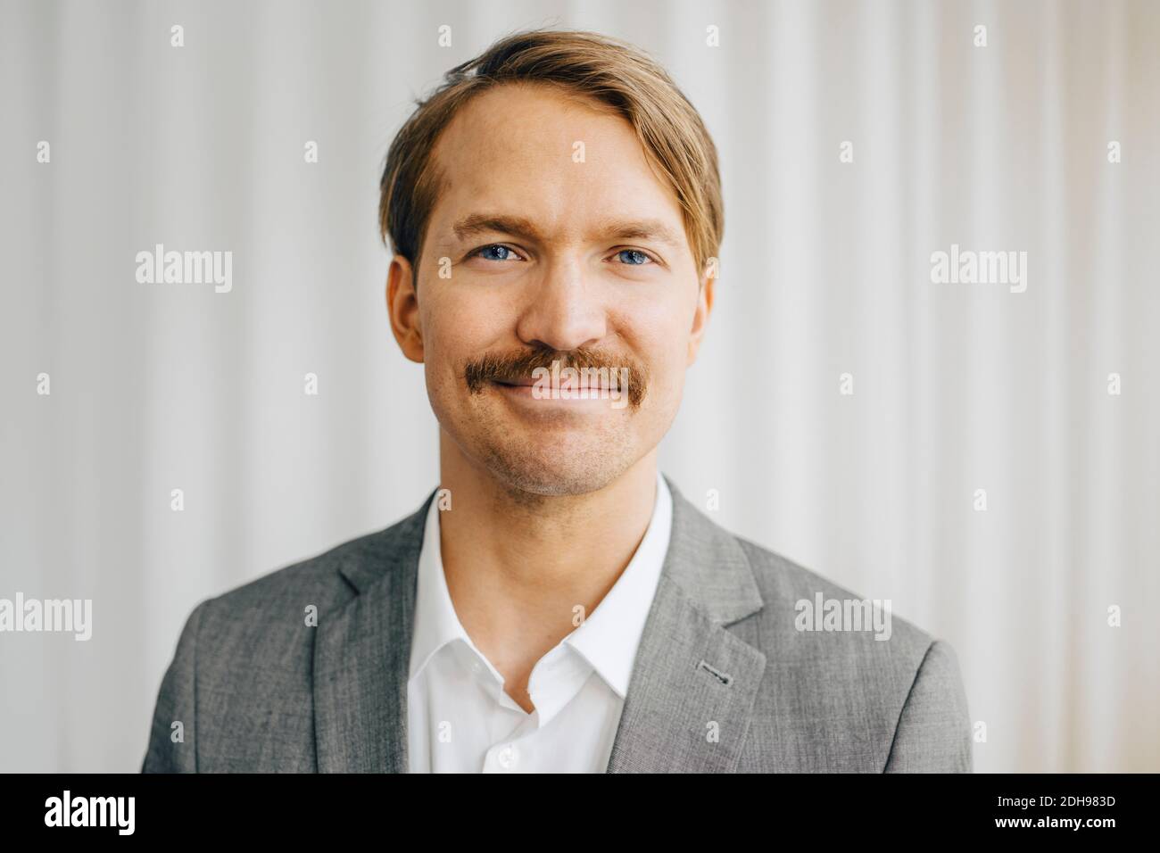 Portrait of businessman standing in office Stock Photo - Alamy