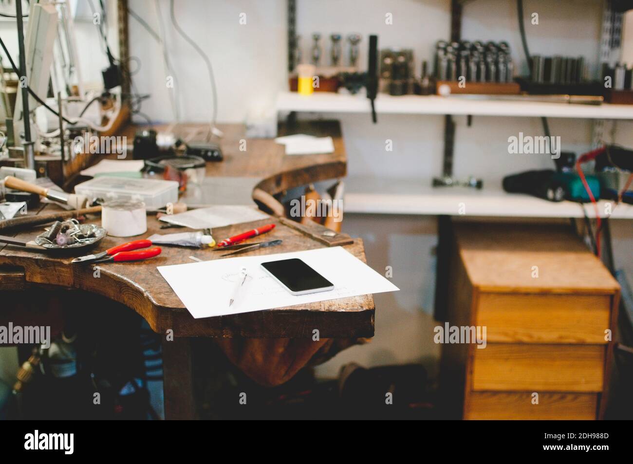 Mobile phone and document on workbench in jewelry workshop Stock Photo