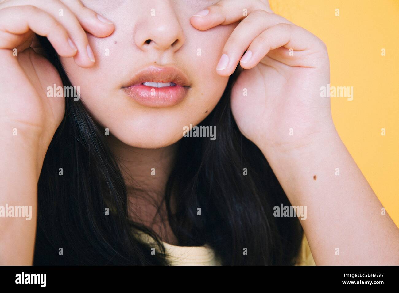 Midsection of girl against yellow background Stock Photo
