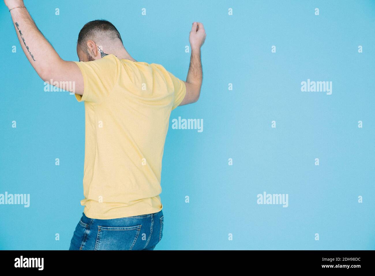 Rear view of man dancing against blue background Stock Photo