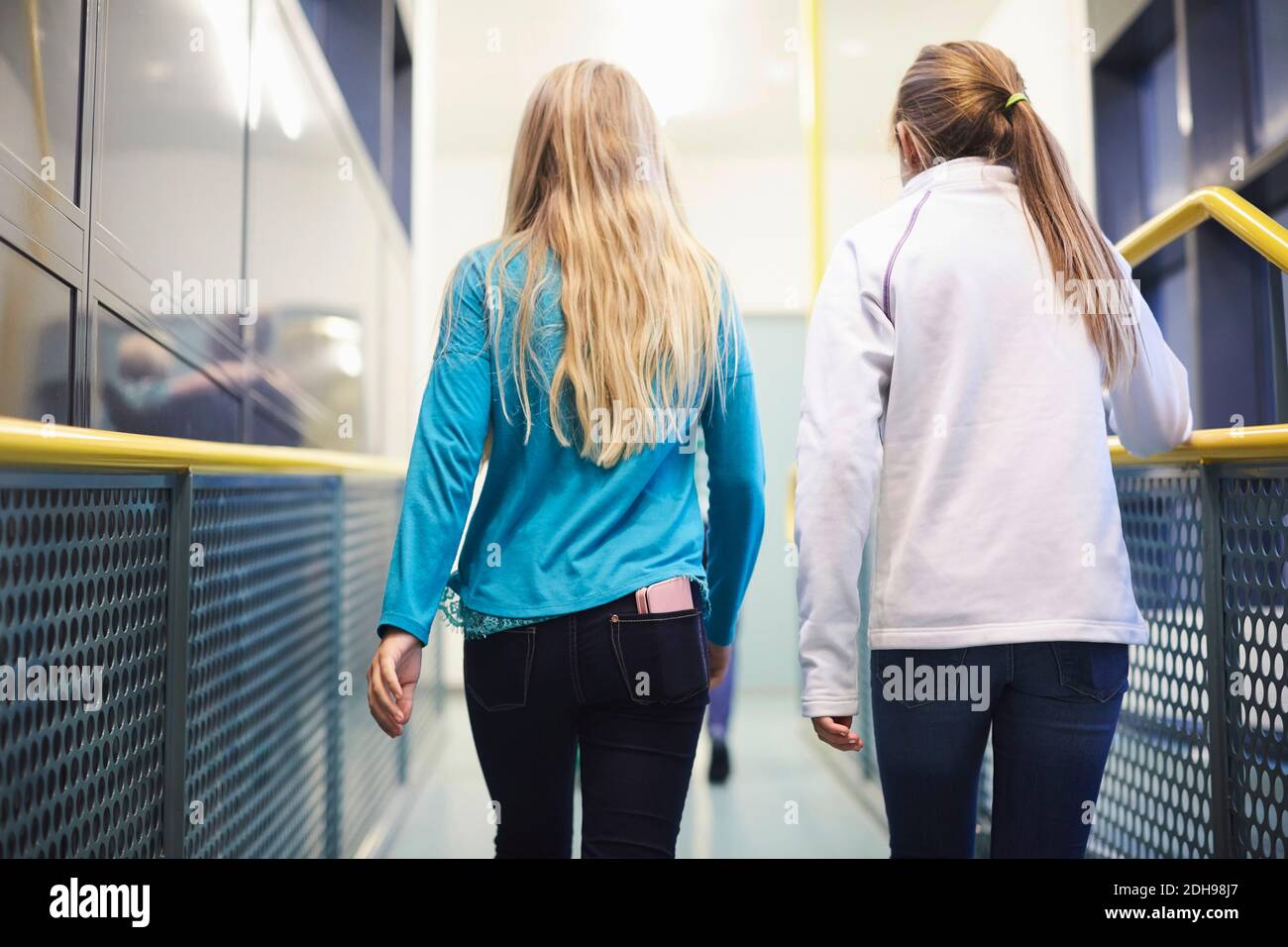 Rear view of girls walking in school corridor Stock Photo