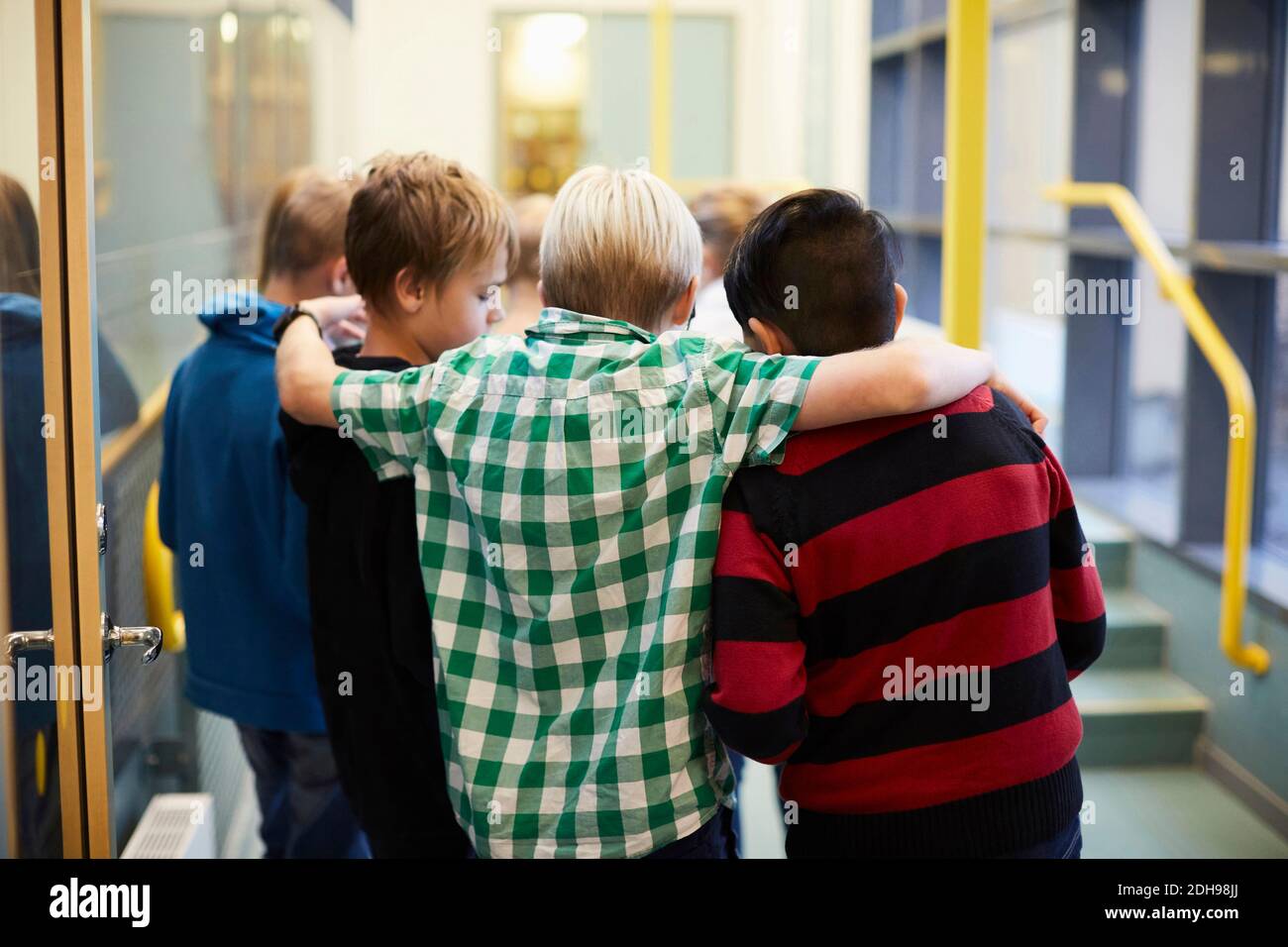 Boys standing arm around in school corridor Stock Photo