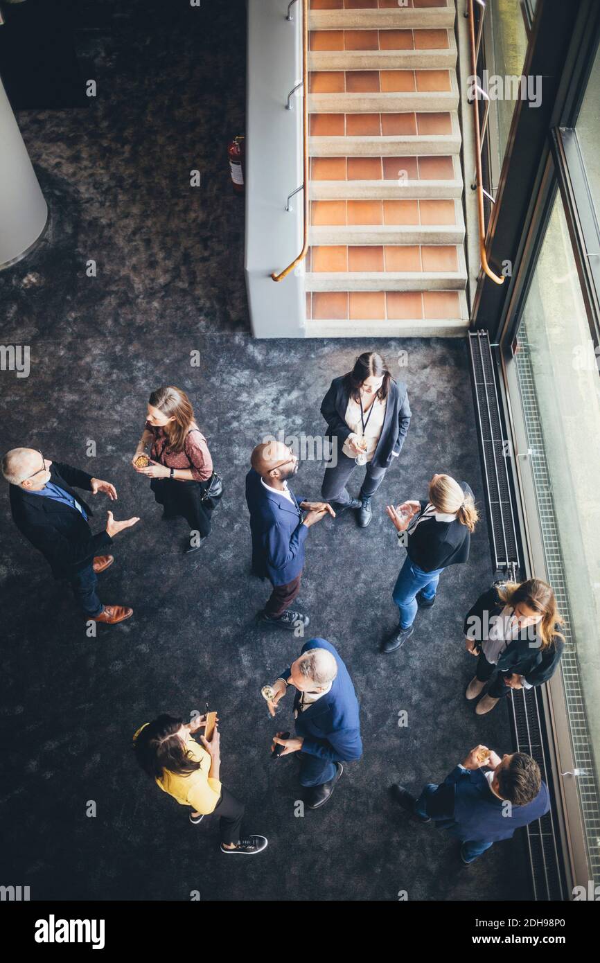 High angle view of business people discussing while standing at workplace Stock Photo