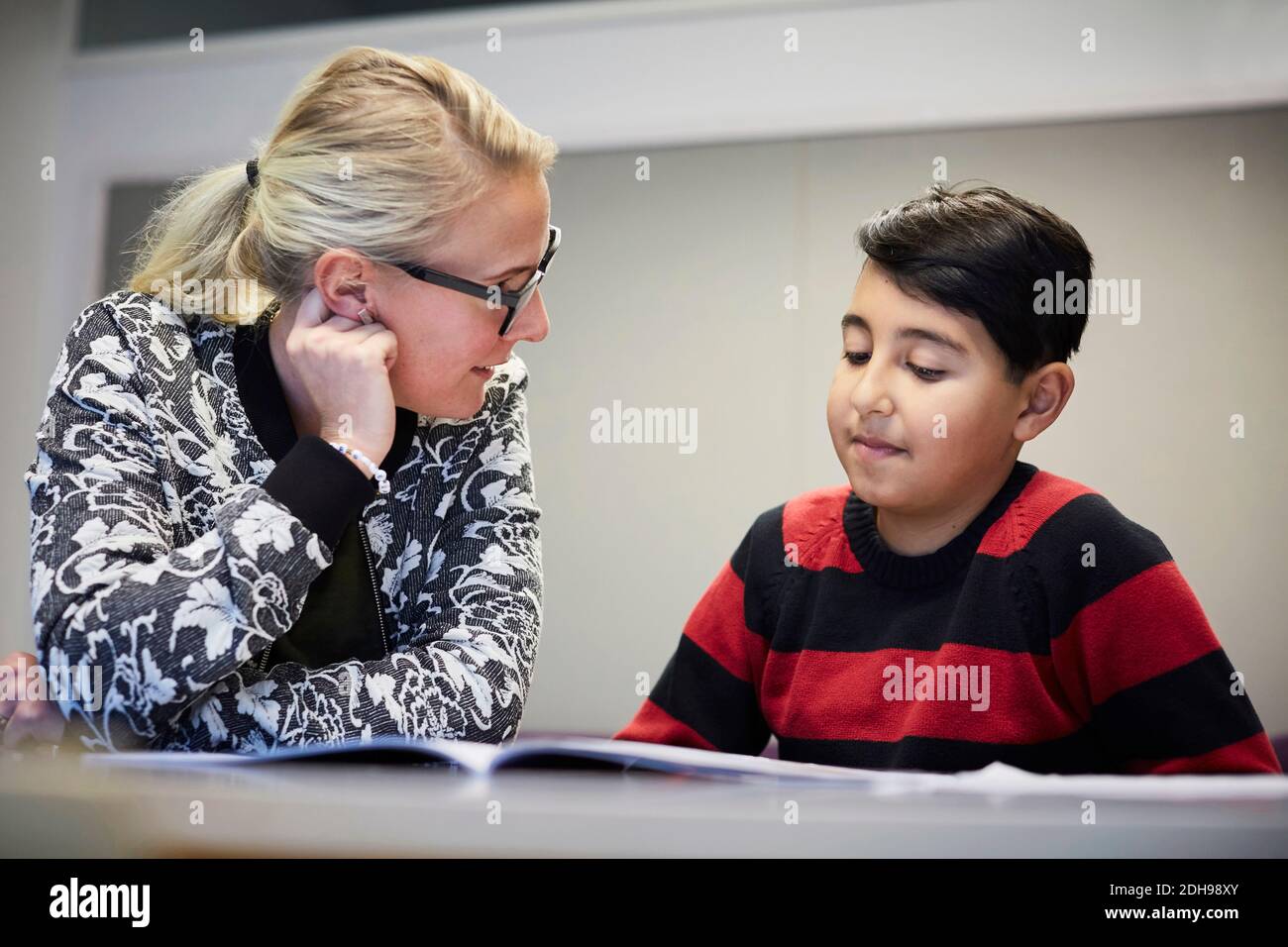 Mid adult teacher teaching boy in classroom Stock Photo