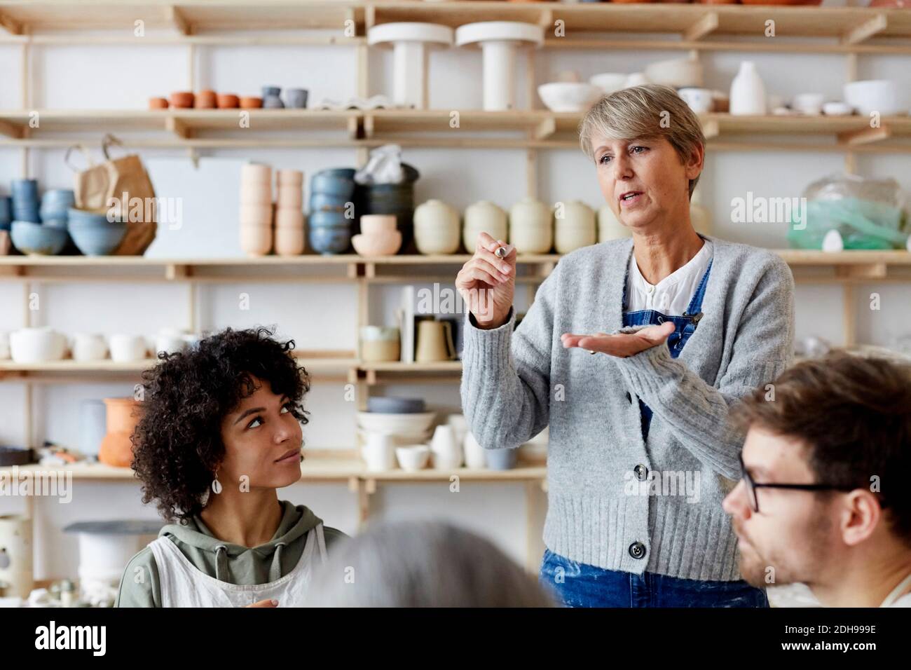 Mature female teacher explaining students in art class Stock Photo