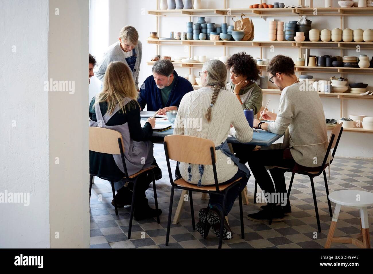 Female instructor examining drawing of students at table during art class Stock Photo