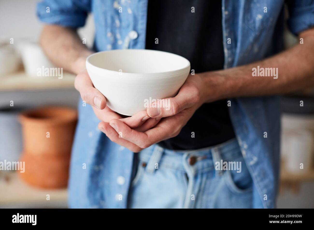 Midsection of man holding bowl in art studio Stock Photo