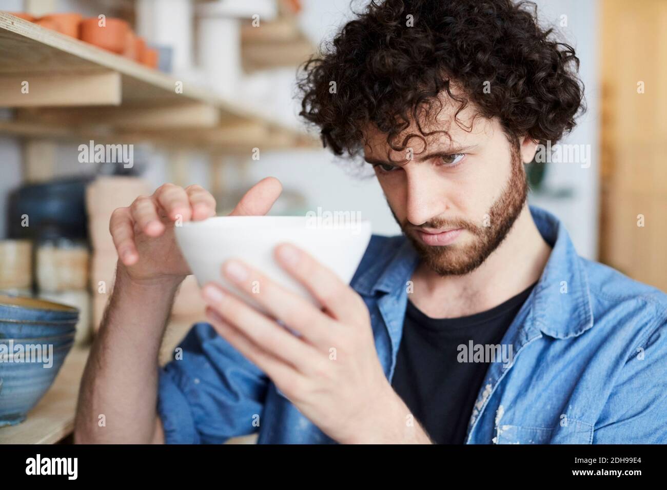 Man examining bowl in pottery class Stock Photo