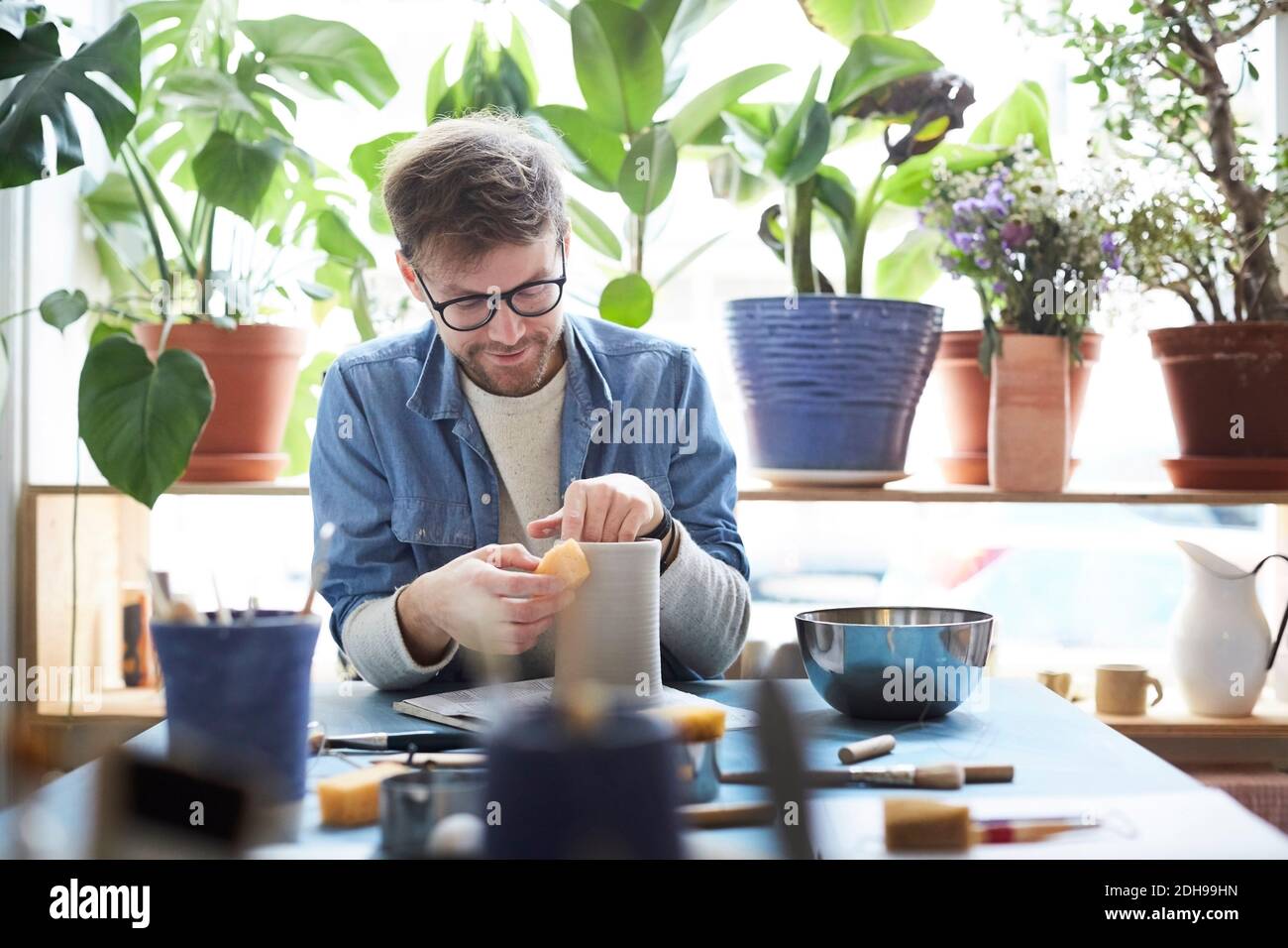 Young man shaping earthenware in pottery class Stock Photo