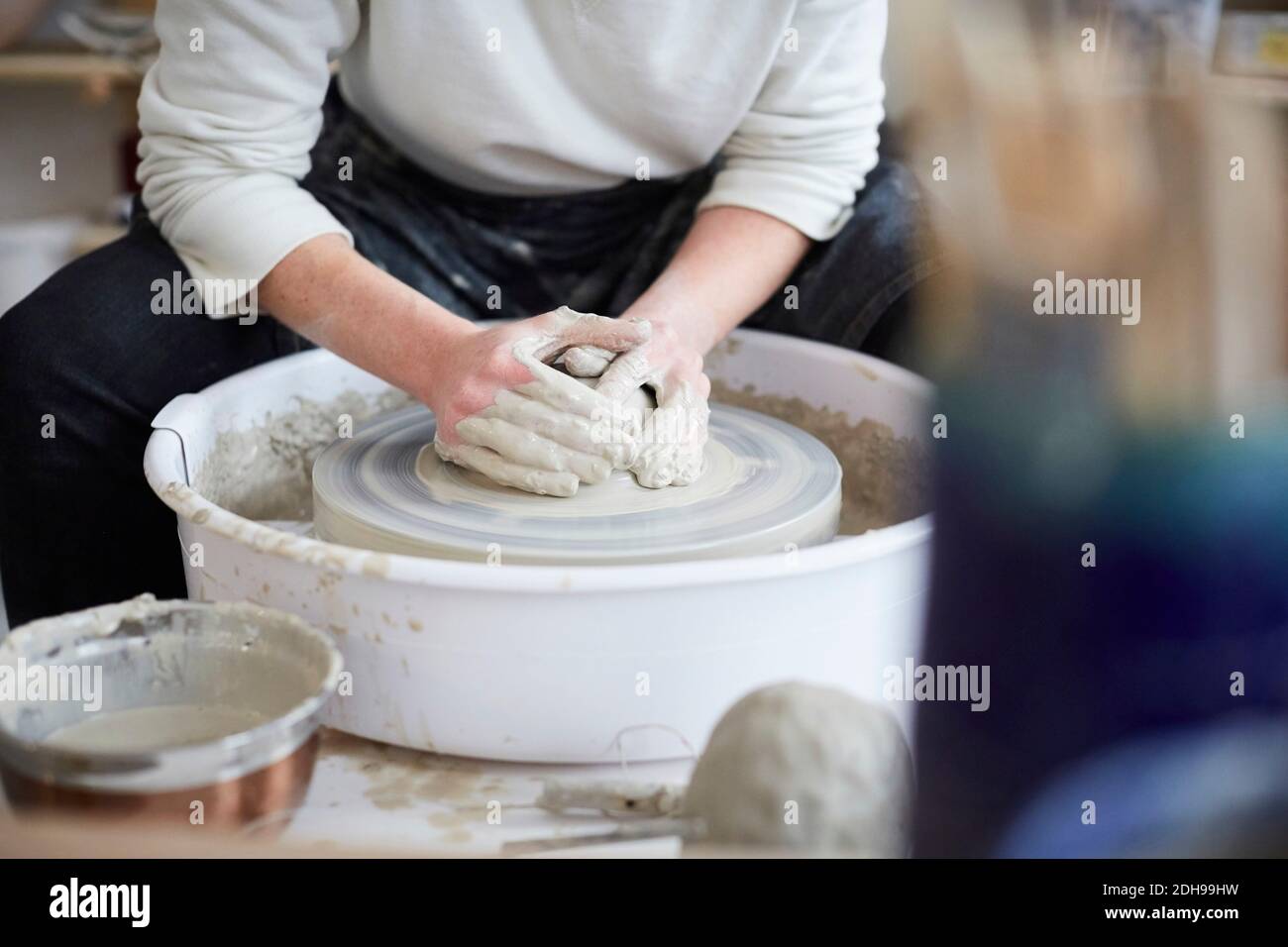 Midsection of woman molding pot in pottery class Stock Photo