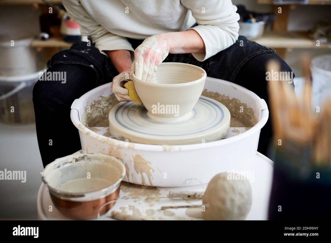 Midsection of mid adult woman molding pot in pottery class Stock Photo