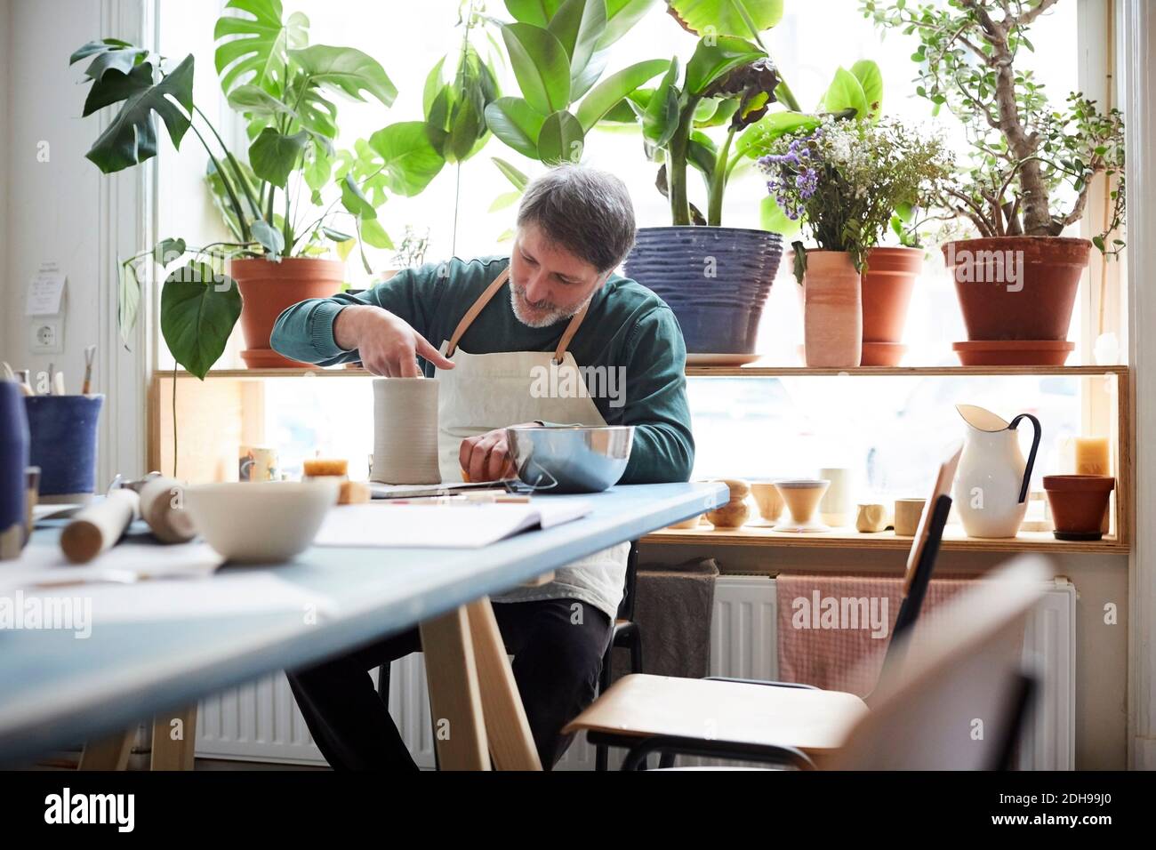 Mature man making craft product in pottery class Stock Photo
