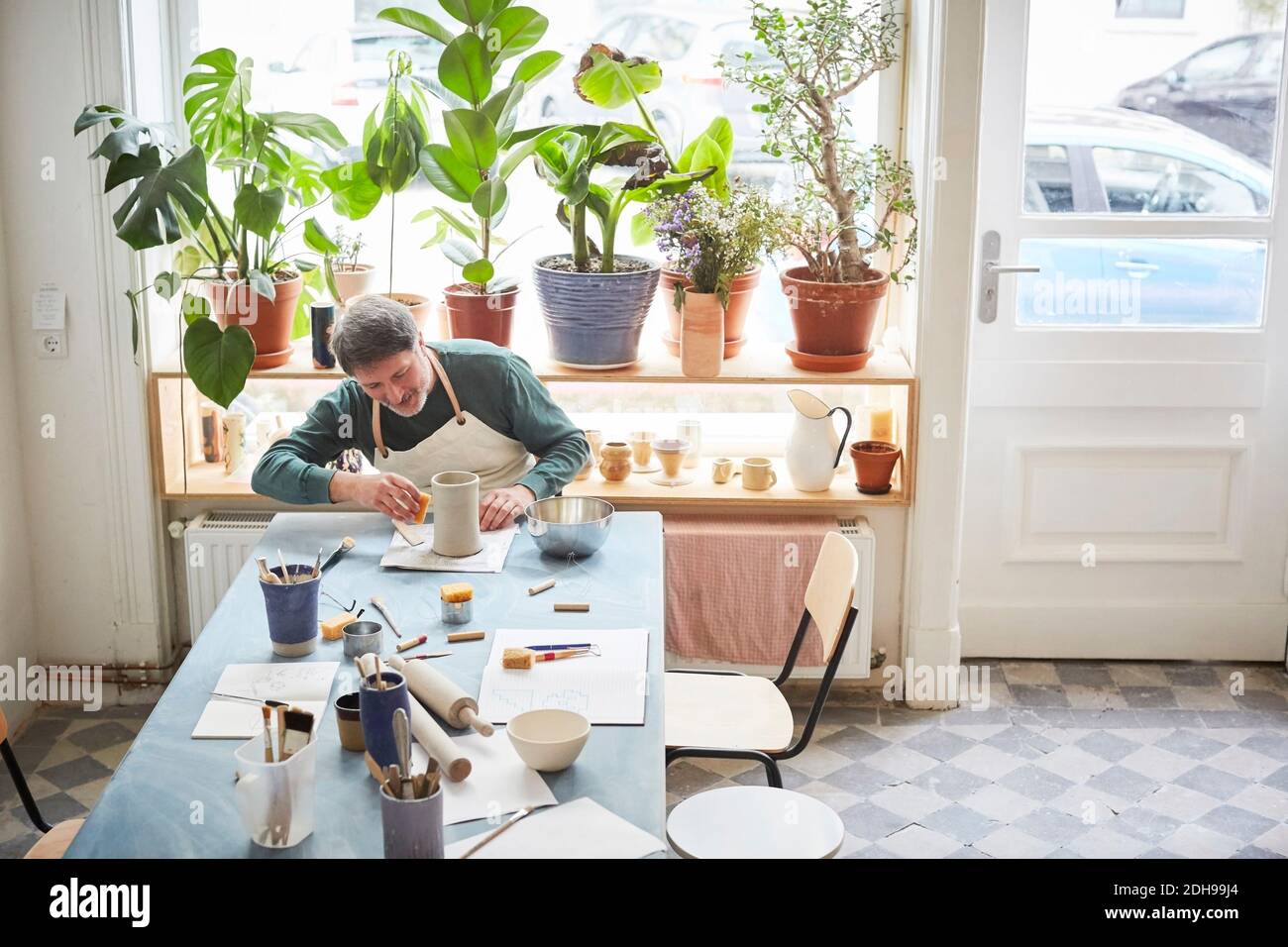 Mature man making craft product at table in pottery class Stock Photo