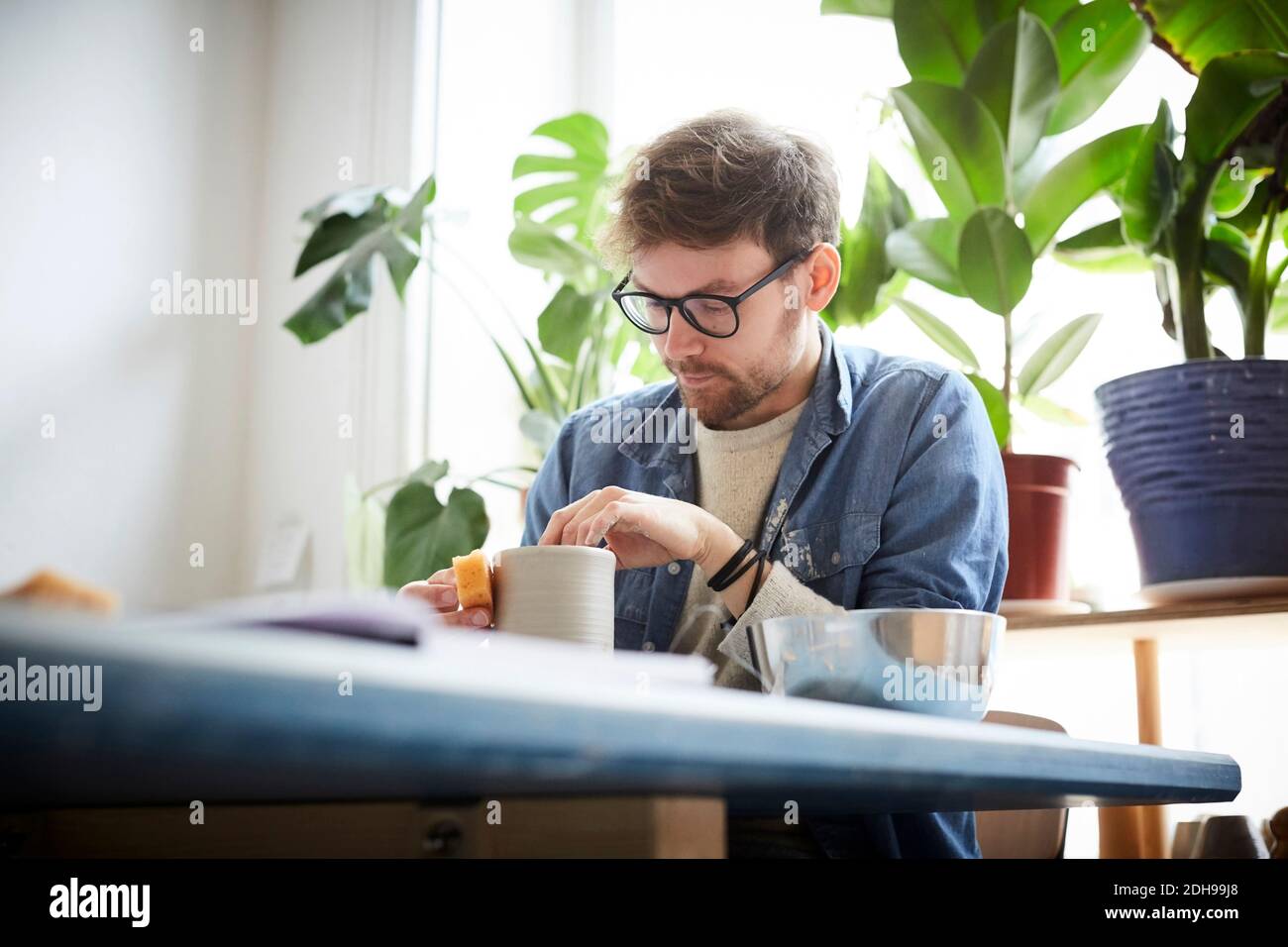 Young man making craft product in pottery class Stock Photo