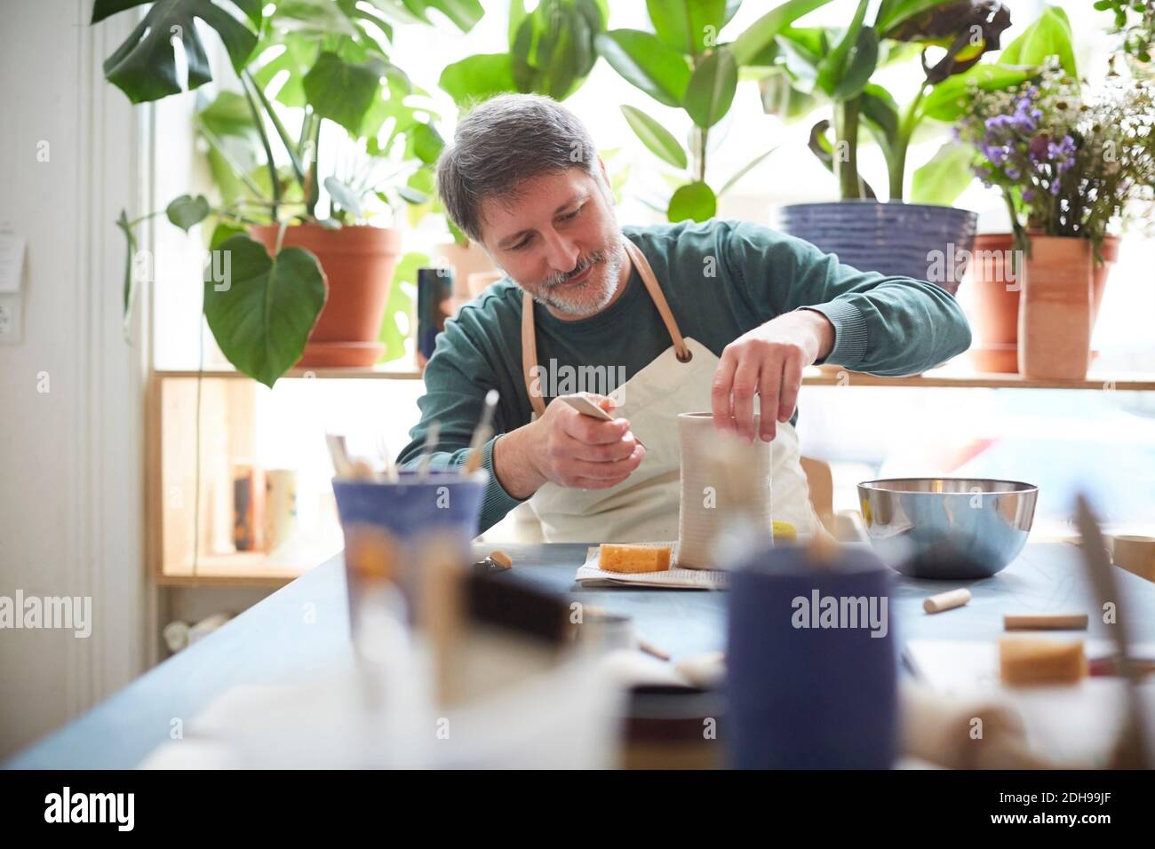 Mature man making craft product in pottery class Stock Photo