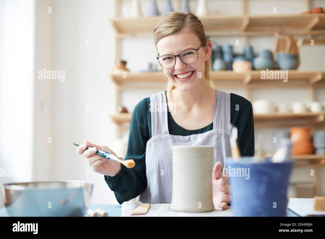 Portrait of smiling young woman learning pottery in art studio Stock Photo
