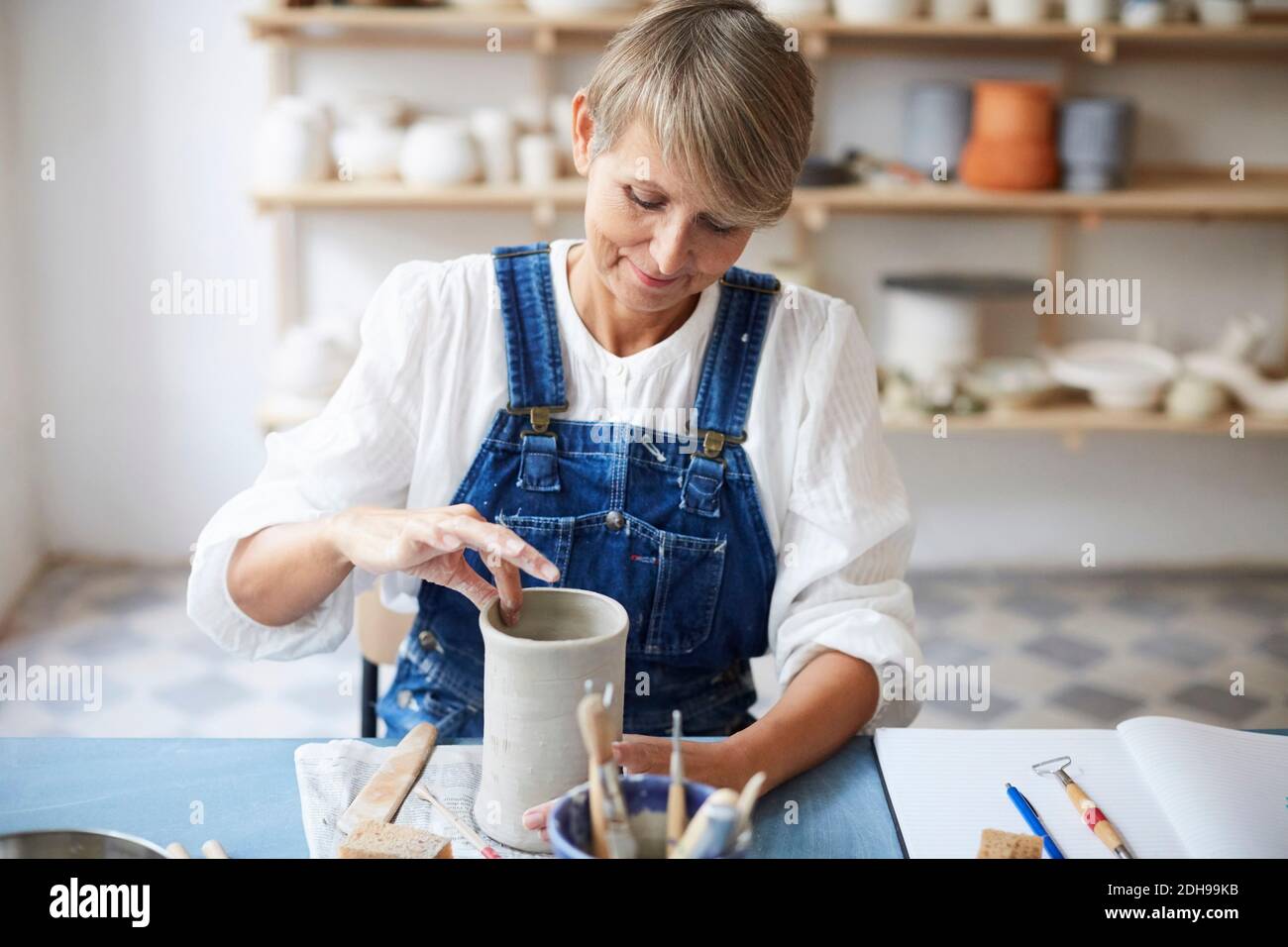 Mature woman molding earthenware at table in art class Stock Photo