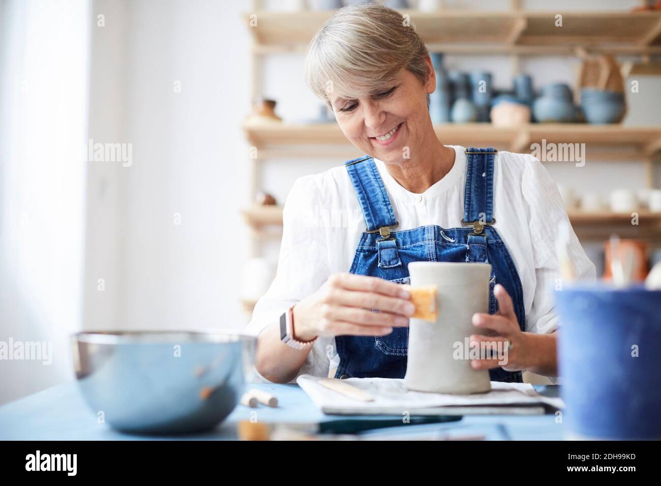 Smiling mature woman learning pottery in art class Stock Photo