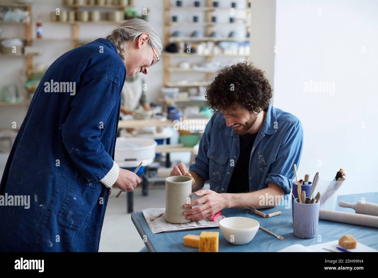 Smiling male and female students learning pottery in art studio Stock Photo