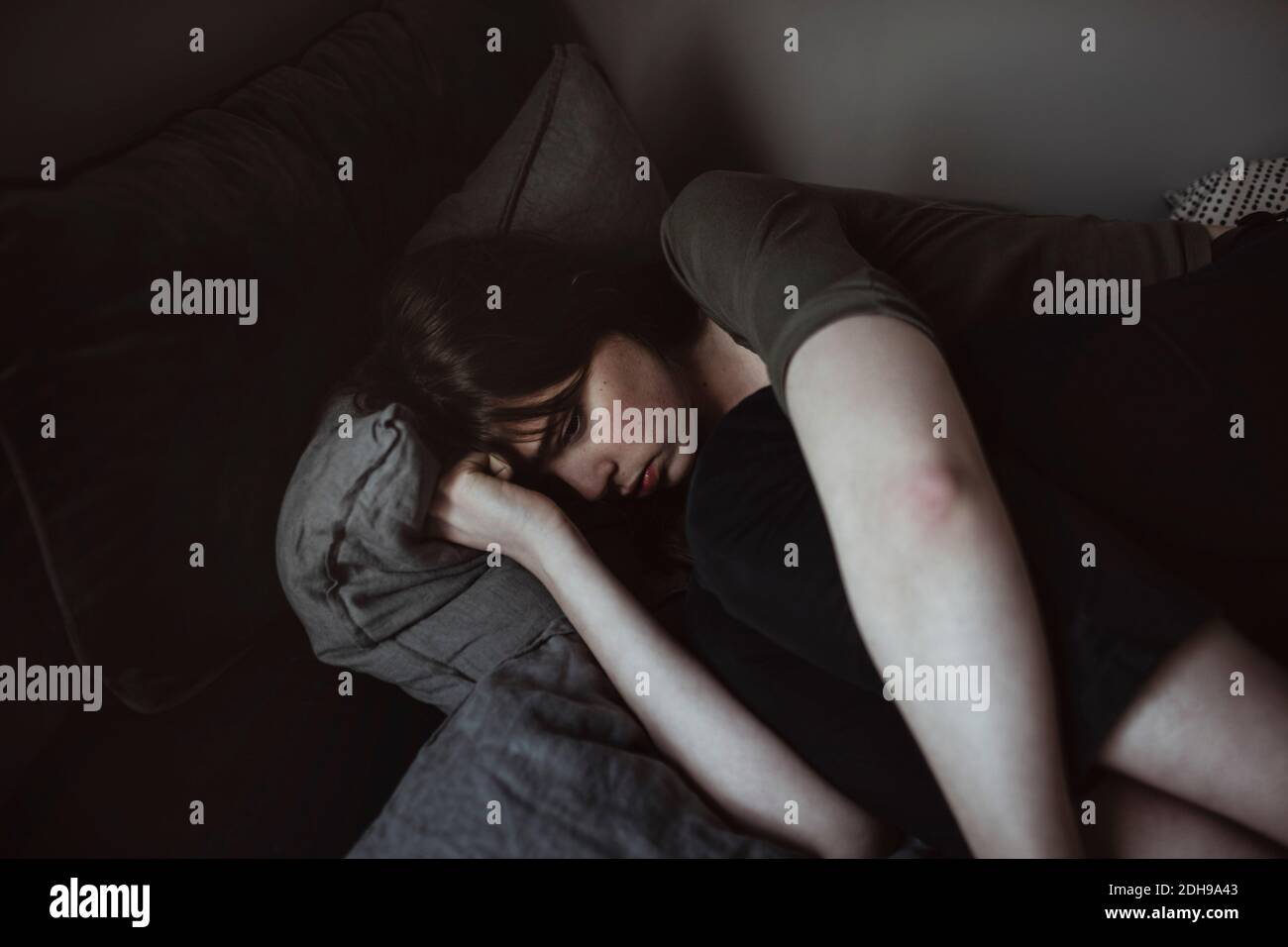 Depressed young woman lying on bed Stock Photo