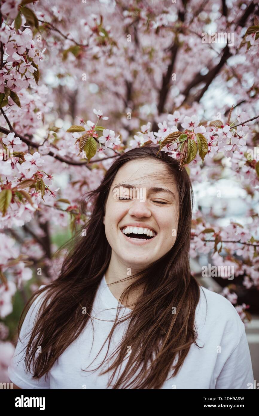 Smiling young woman standing against pink tree Stock Photo