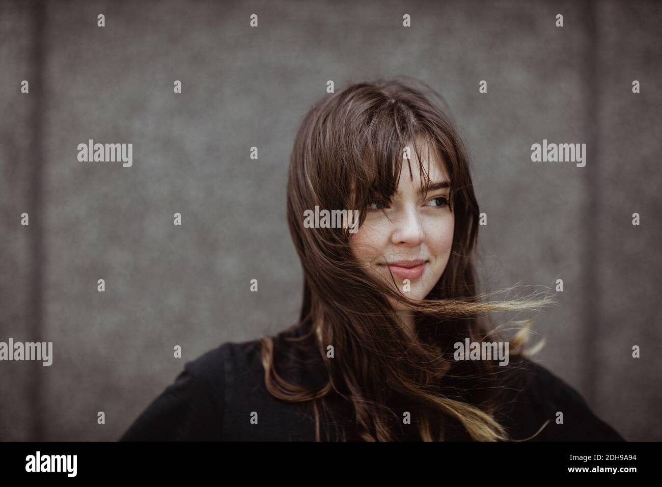 Smiling woman looking away while standing outdoors Stock Photo