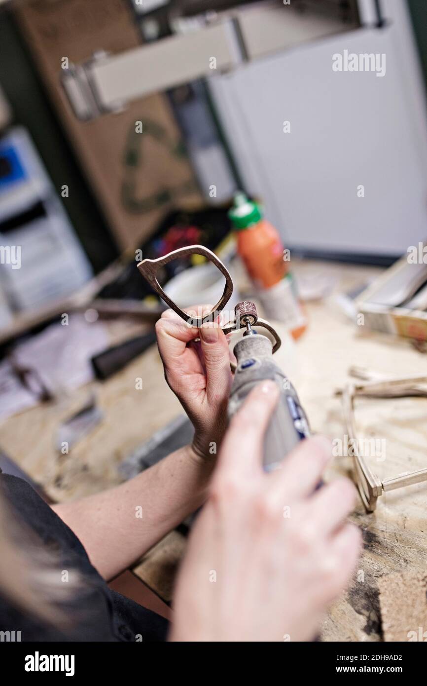 Cropped image of female owner making eyeglasses with work tool at workshop Stock Photo