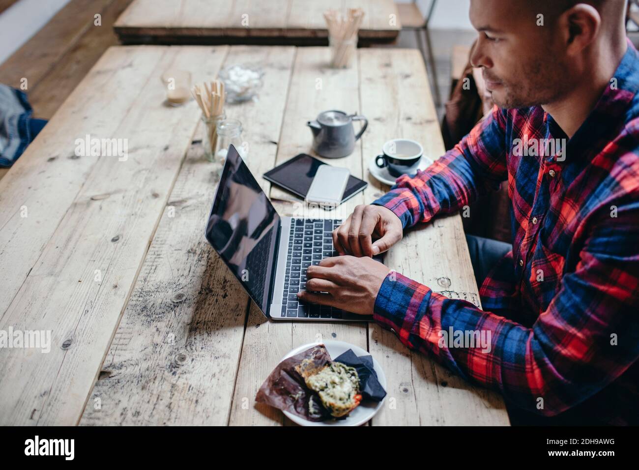 Side view of mid adult man using laptop at table in coffee shop Stock Photo