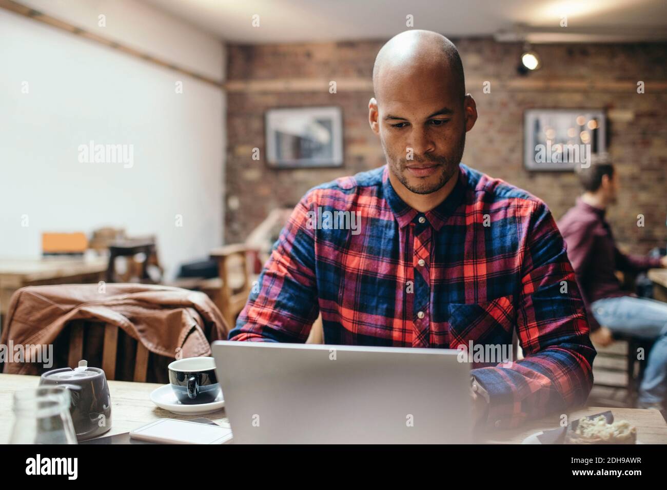 Mid adult man using laptop at table in coffee shop Stock Photo