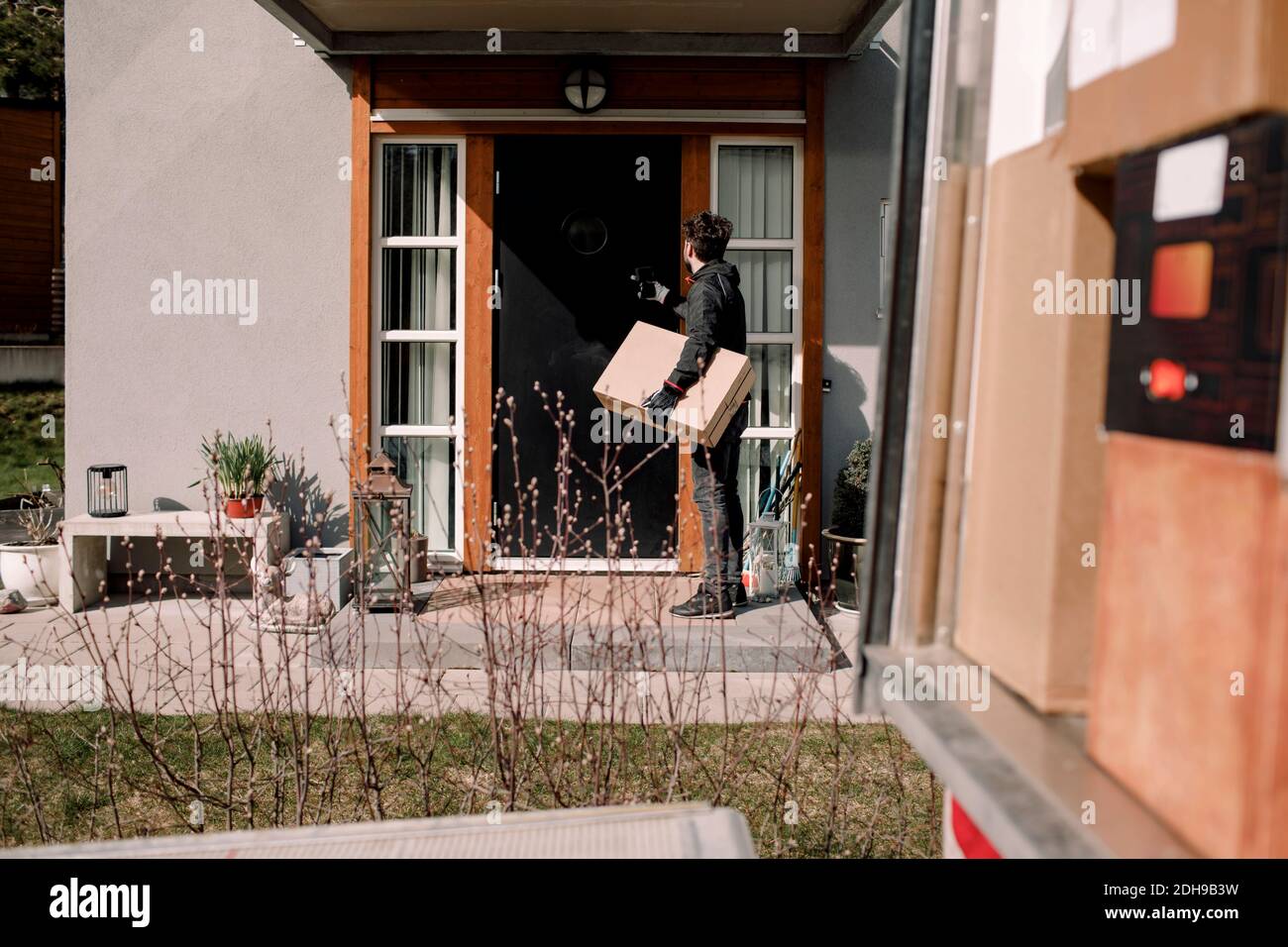 Delivery man with package at entrance of house Stock Photo