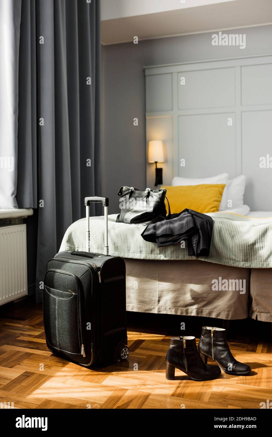 Wheeled luggage and womenswear in hotel room Stock Photo