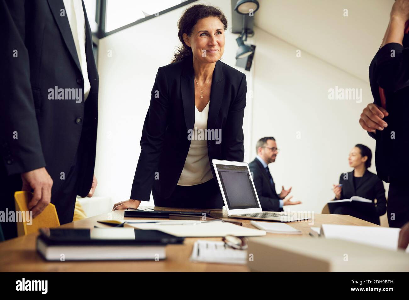 Smiling female professional looking at colleagues during meeting in law firm Stock Photo