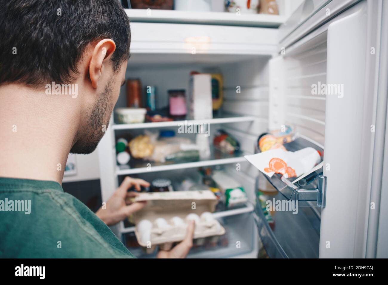 Man holding egg carton by refrigerator in kitchen Stock Photo Alamy