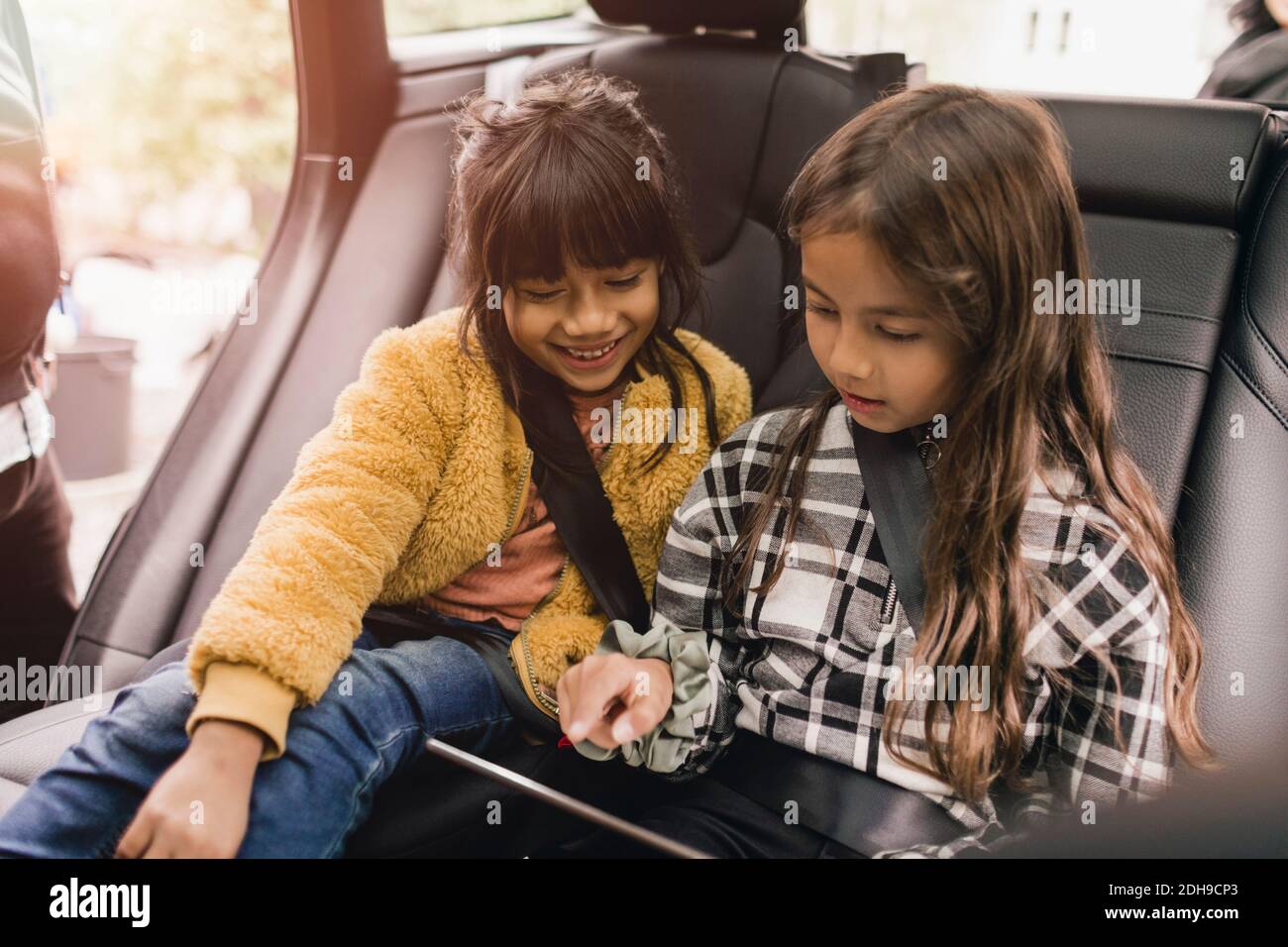 Sisters using digital tablet while sitting in electric car Stock Photo