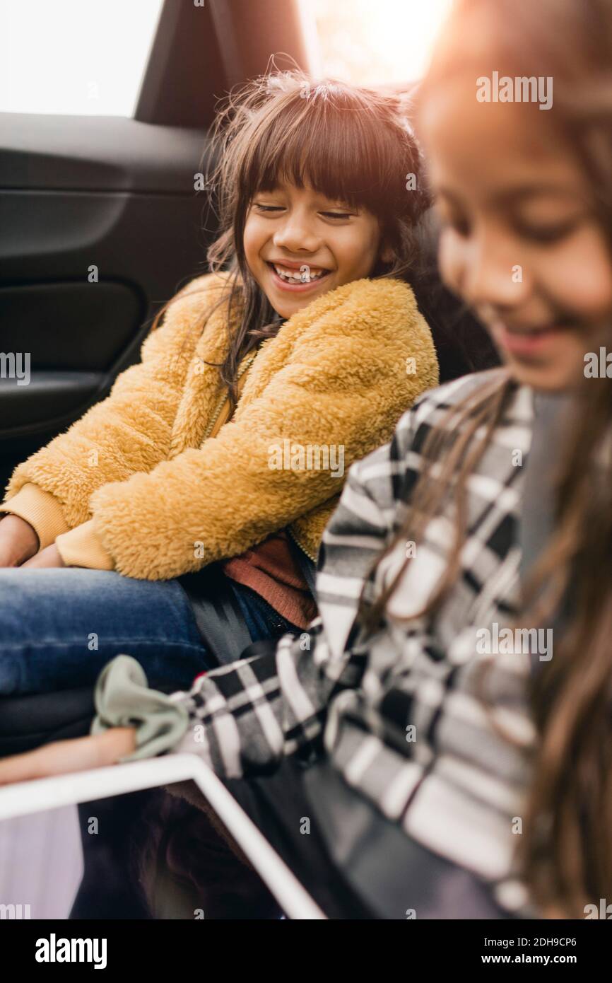 Smiling sisters using digital tablet while traveling in electric car Stock Photo