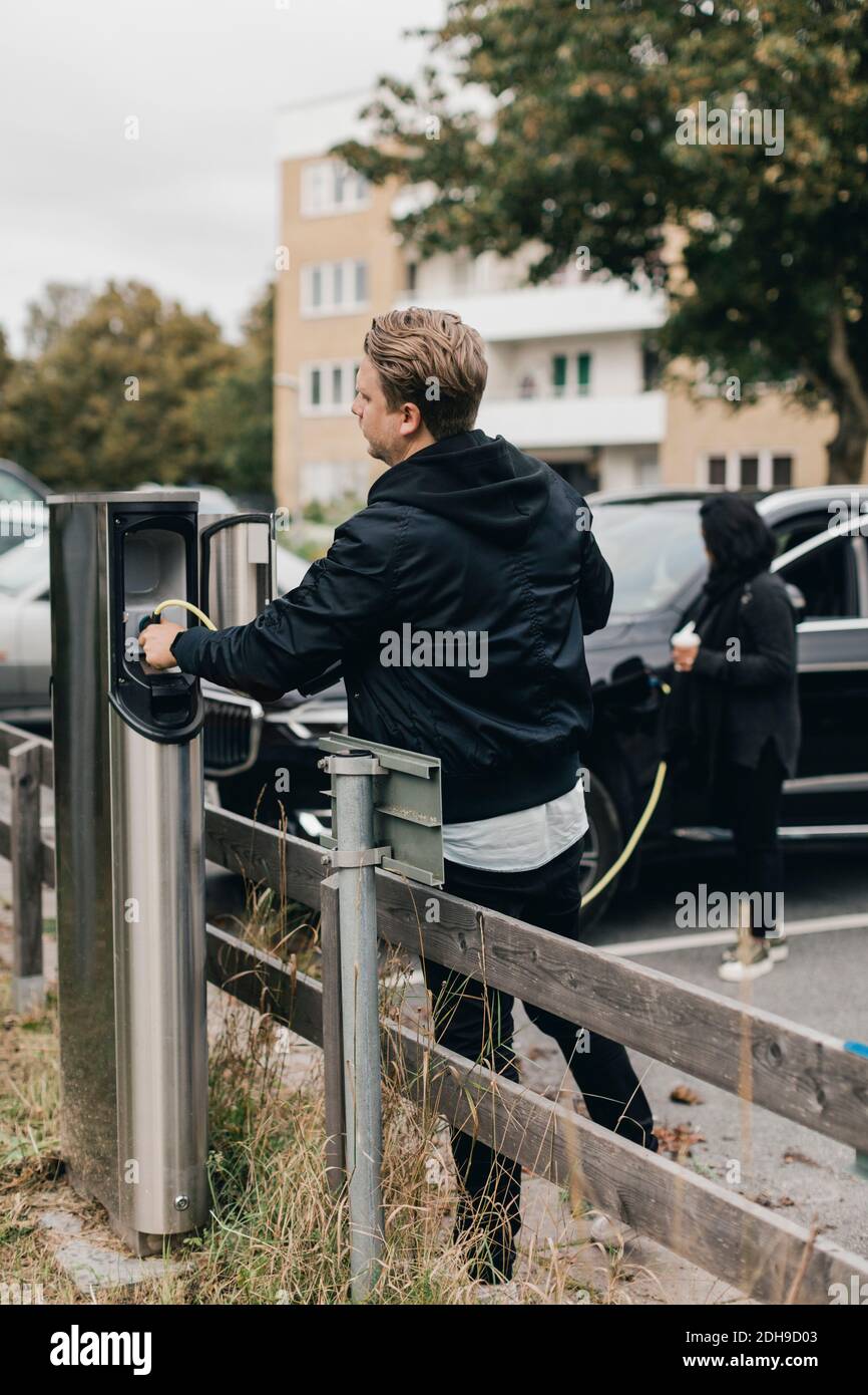 Man connecting cable at electric car charging station Stock Photo