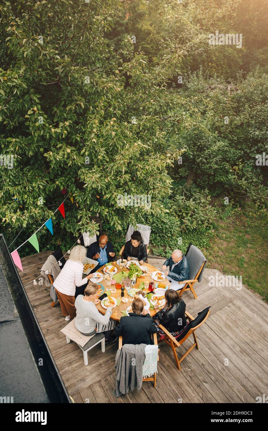 High angle view of senior woman serving friends sitting at dining table during garden party in back yard Stock Photo