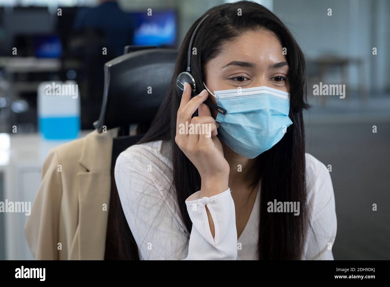 Businesswoman wearing face mask using headset at modern office Stock ...