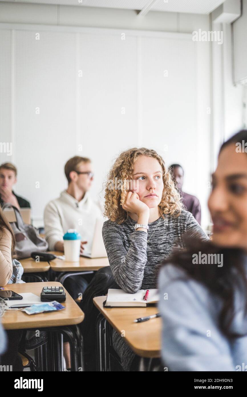 Thoughtful young female student at desk in classroom Stock Photo - Alamy