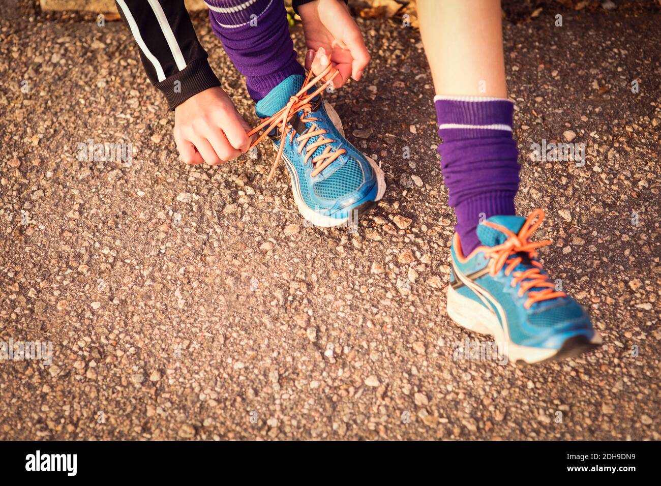 Low section of girl tying shoelace on footpath Stock Photo
