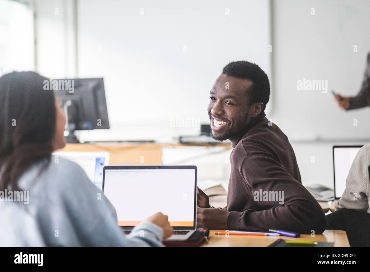 Smiling young man talking with female student in classroom Stock Photo ...