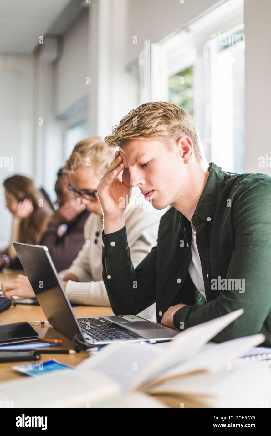 Serious young man using laptop in classroom Stock Photo