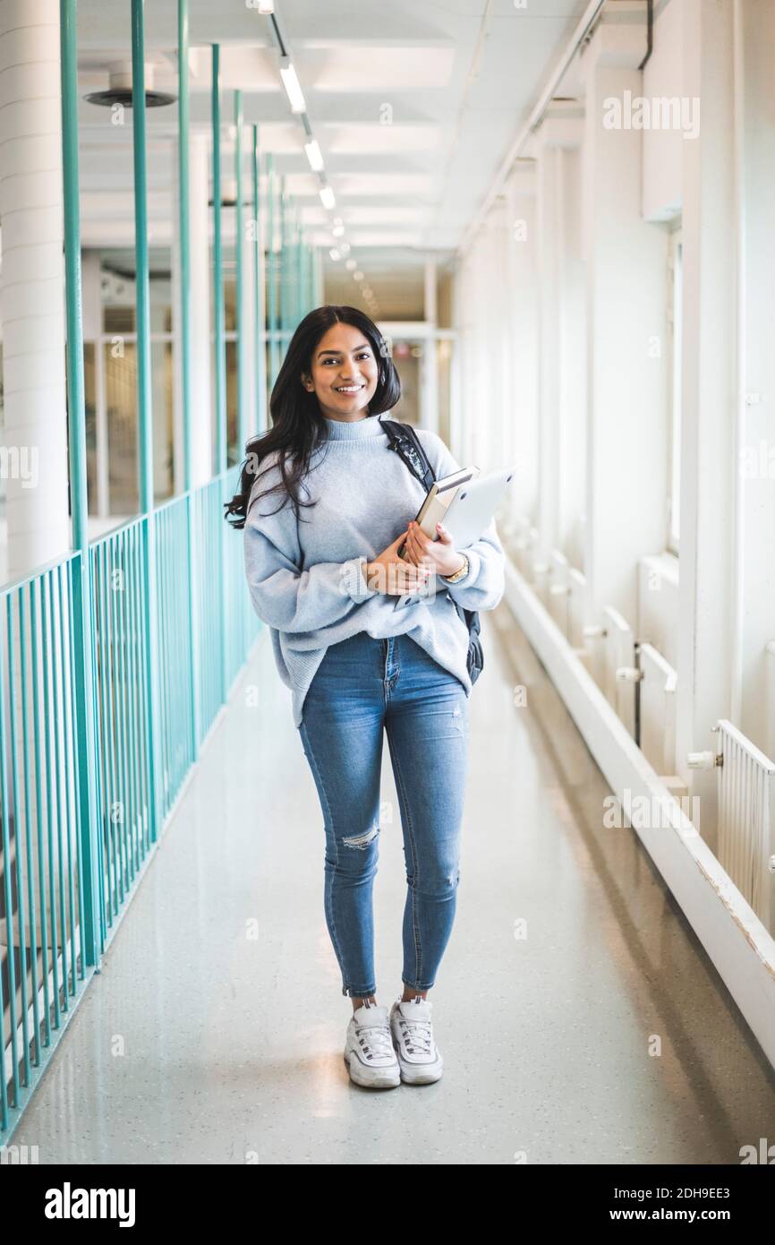 Portrait of young female student standing in corridor of university Stock Photo