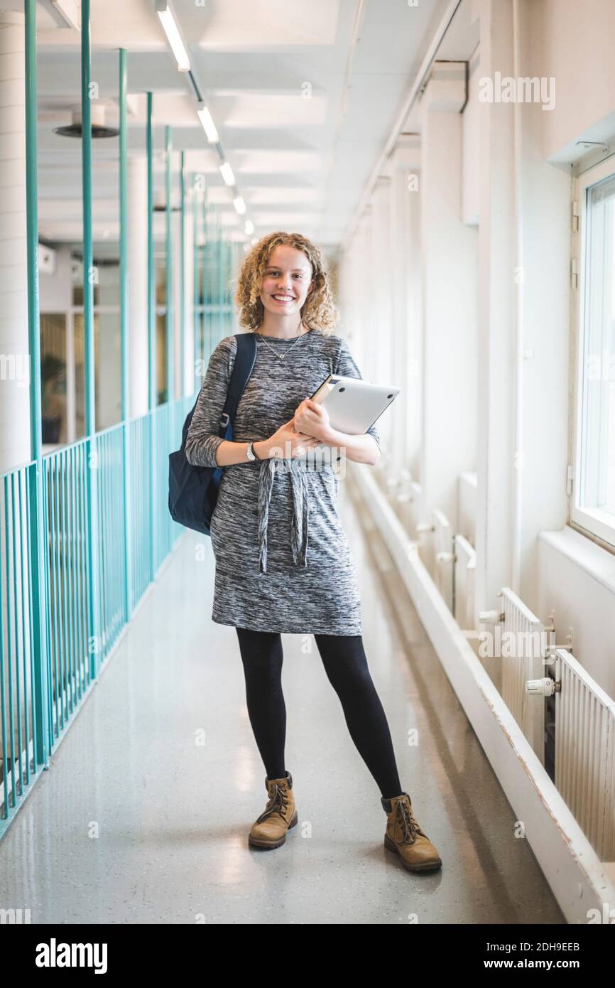 Portrait of smiling young female student in corridor of university Stock Photo